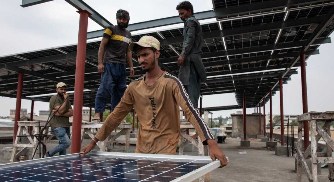 Workers install solar panels on the rooftop of a business on June 30, 2025 in Islamabad, Pakistan.