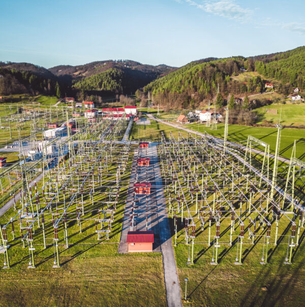 Electrical power substation in the country side of Slovenia. Fields and forests surrounding the power station in the suburbs. Aerial view.