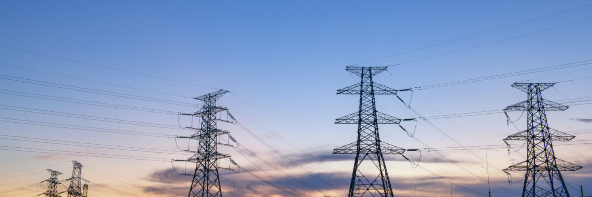 electricity transmission pylon silhouetted against blue sky at dusk