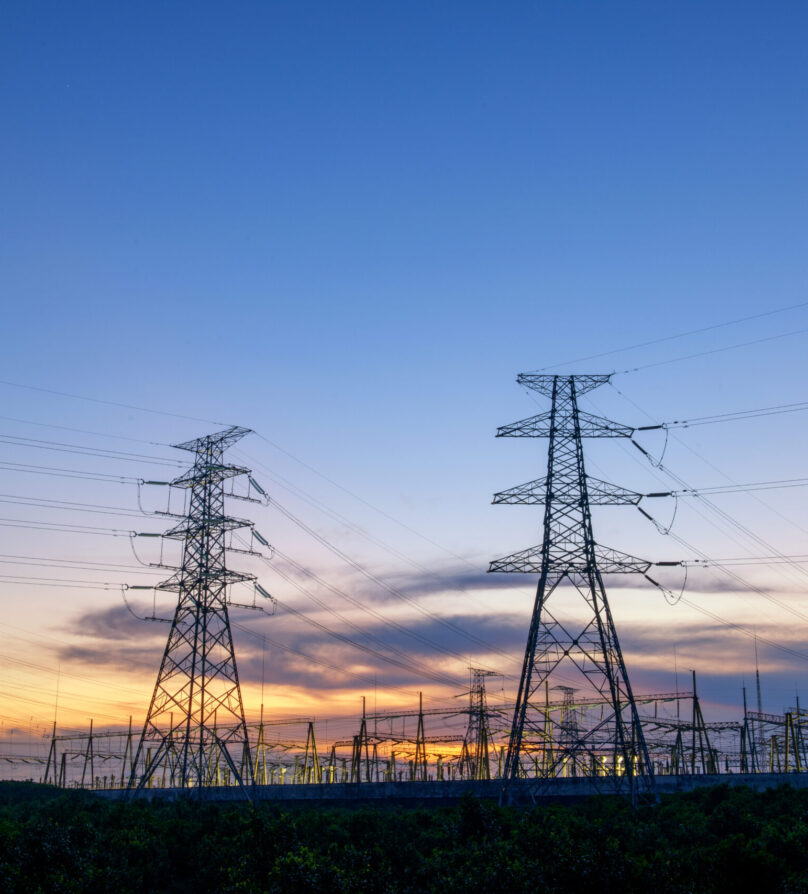 electricity transmission pylon silhouetted against blue sky at dusk